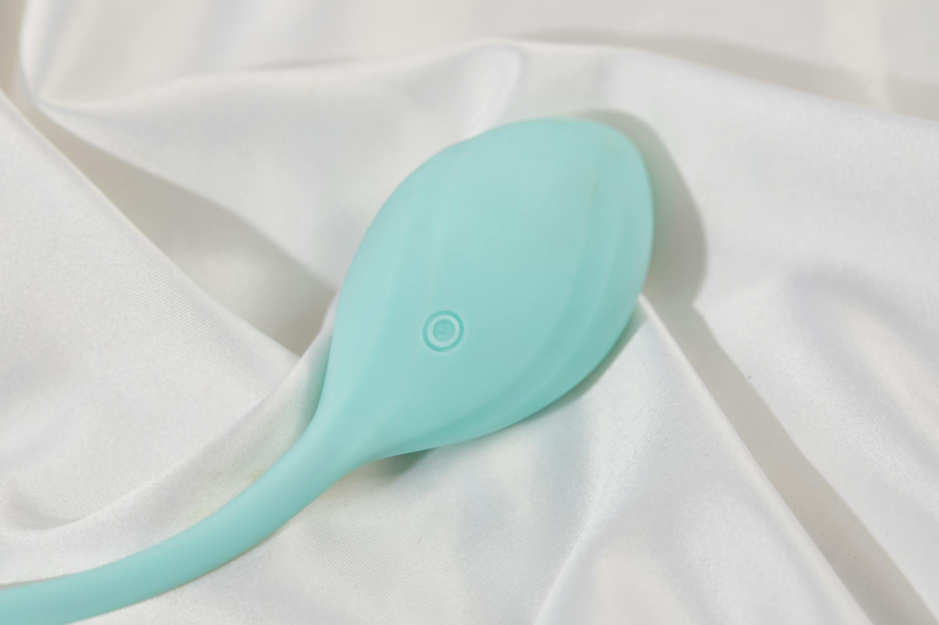 Ein stilvoller hellblauer Vibrator auf seidenem Stoff, symbolisiert moderne Sexualwellness nach chirurgischen Eingriffen