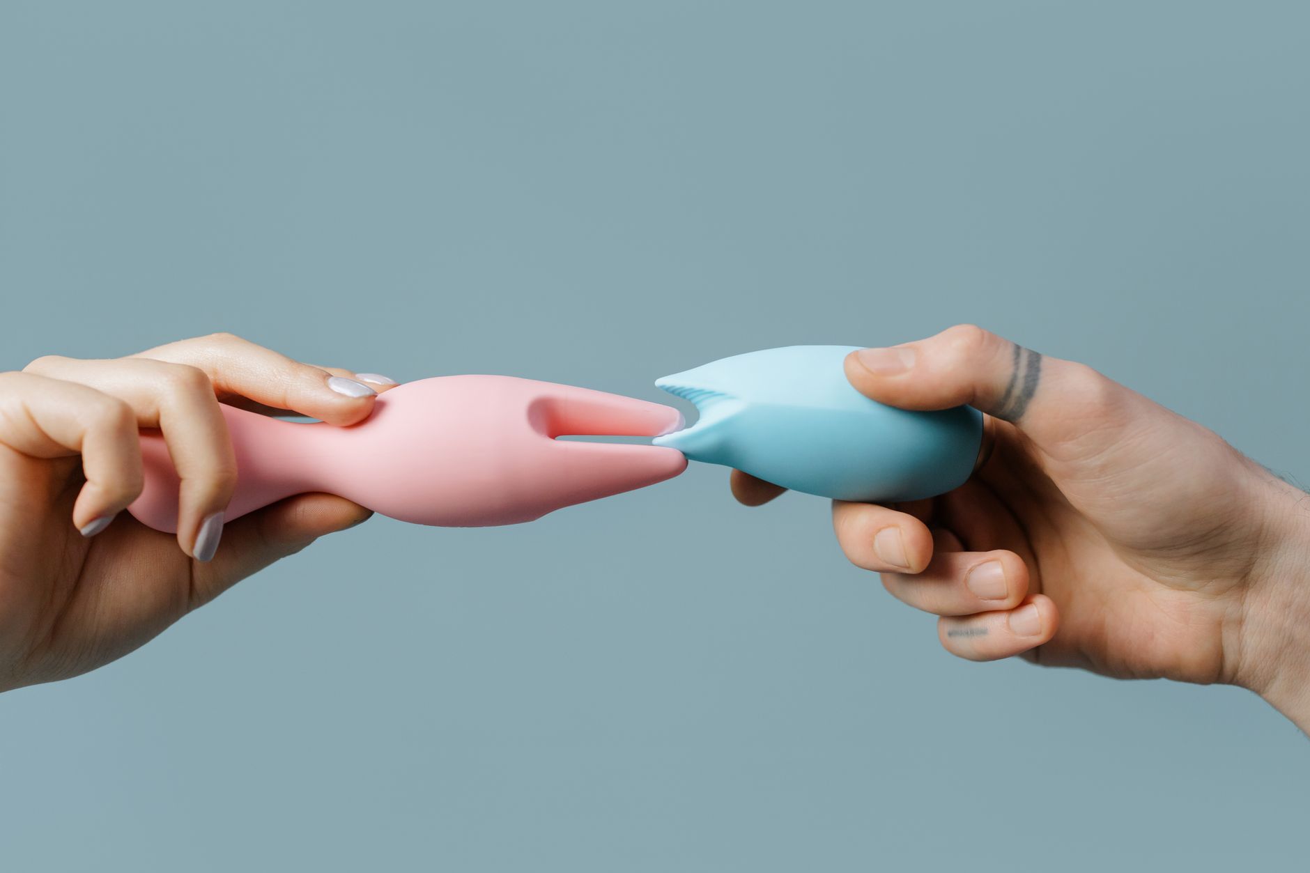 Close-up of a hand holding a sleek blue vibrator against a purple background, representing gentle sensation restoration