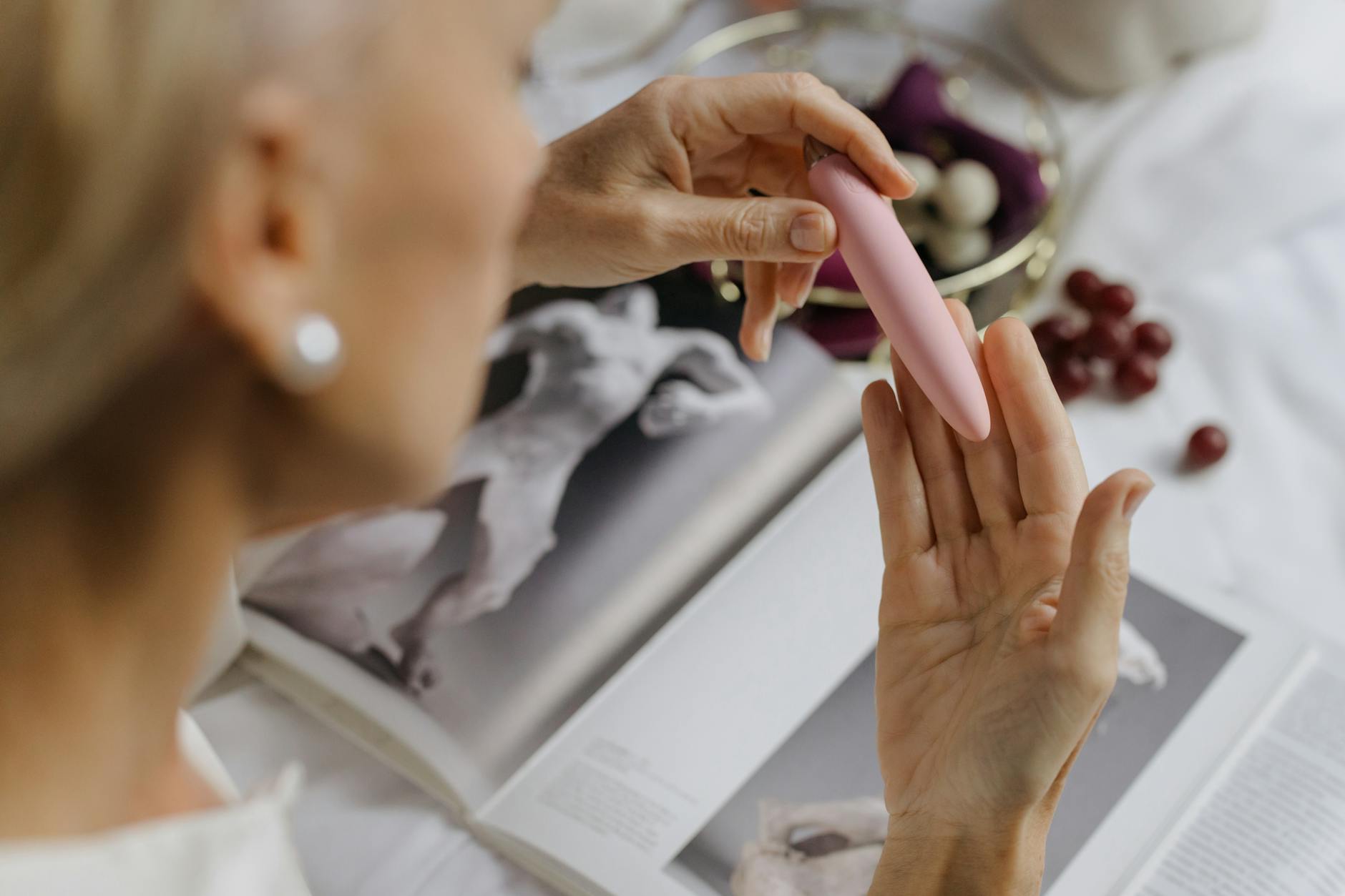 Nahaufnahme von Händen, die einen blauen persönlichen Massager gegen einen gestrickten Pullover halten.