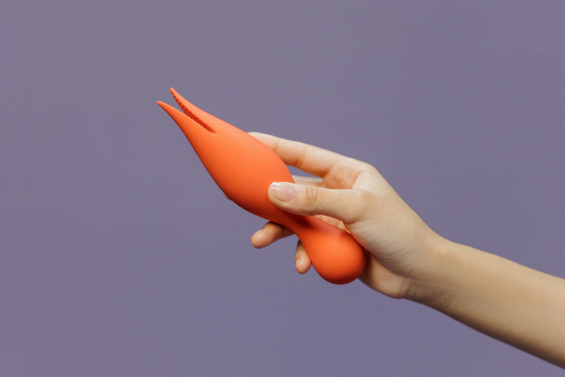 A hand holding a bright yellow lemon on a soft pink background, symbolizing the juicy intensity of pleasure with a lemon vibrator.