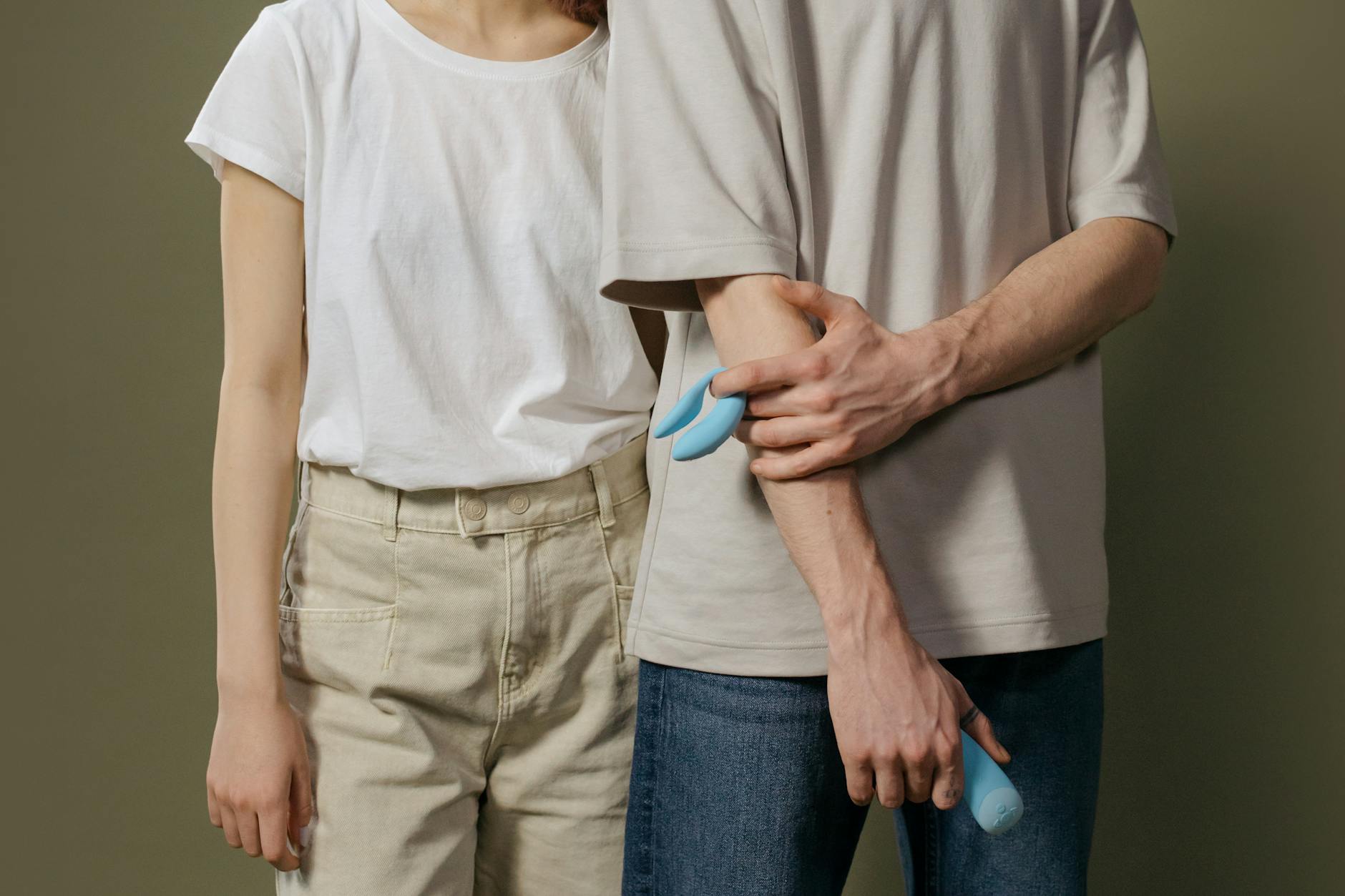 Eine Hand hält einen orangefarbenen Zitronenvibrator vor minimalistische lila Kulisse