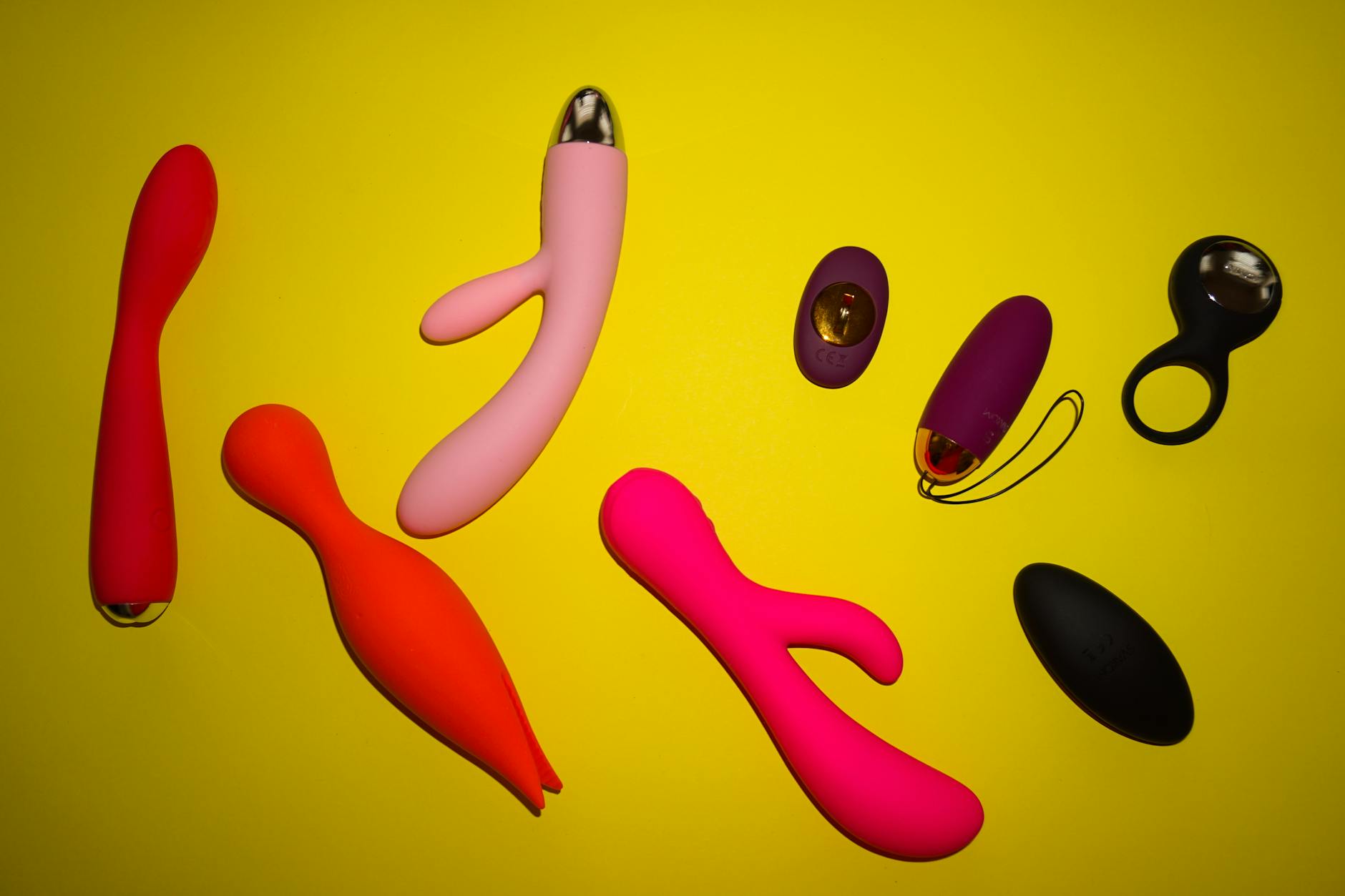 Bunte Anordnung verschiedener Zitronenvibratoren und Sextoys auf gelbem Hintergrund, die Vielfalt und Design zeigen